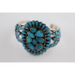 A black opal and silver cluster bangle, the centre oval cluster with eight rub over set oval and