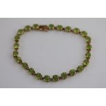 A peridot 9ct yellow gold line bracelet, comprising twenty-four claw set round mixed cut period,