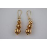 A pair of yellow metal drop earrings, three graduated textured spheres, shepherd hook ear