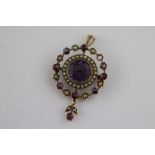 An Edwardian amethyst and seed pearl rose gold pendant brooch, openwork design, the central round