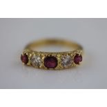 A ruby and diamond five stone 18ct yellow gold ring, the central largest round mixed cut ruby