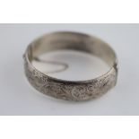 A silver hinged bangle, the upper half with engraved foliate scroll decoration, Birmingham 1959,