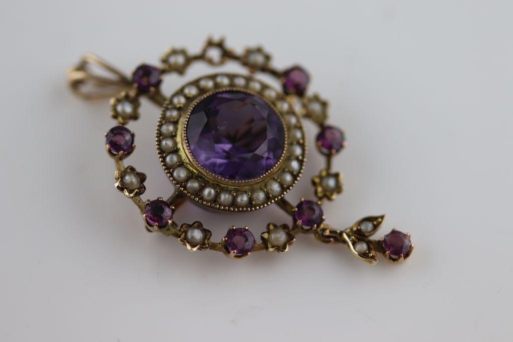 An Edwardian amethyst and seed pearl rose gold pendant brooch, openwork ...