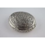 An Asian white metal oval snuff box, repousse floral and scroll decoration, approximately 6cm by 7.