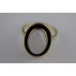 A precious white opal and black enamel unmarked yellow gold ring, the centre oval cabochon cut