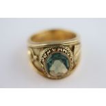 A Royal Marines Commando green topaz 18ct yellow gold ring, the oval faceted rub over flush set