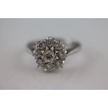 A diamond 18ct white gold flower head cluster ring, the centre claw set round brilliant cut