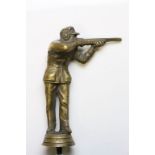 A brass car mascot of a shotgun shooter clay pigeon