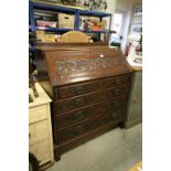 19th century Oak Bureau with hinged drop front over four long drawers, heavy scroll carving to front