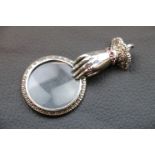 A silver magnifying glass pendant necklace set with rubies