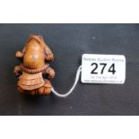 Carved hardwood Japanese netsuke of a seated toad wearing an apron, signed to reverse, height