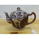 An Art Nouveau treacle glaze teapot with white metal overlay, the central flower motif with