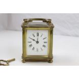 Brass carriage clock raised on fur turned feet, white enamel dial with black Roman numerals and