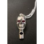A silver skull headed whistle pendent with ruby eyes.