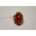 A silver dress ring with large central cabochon amber.