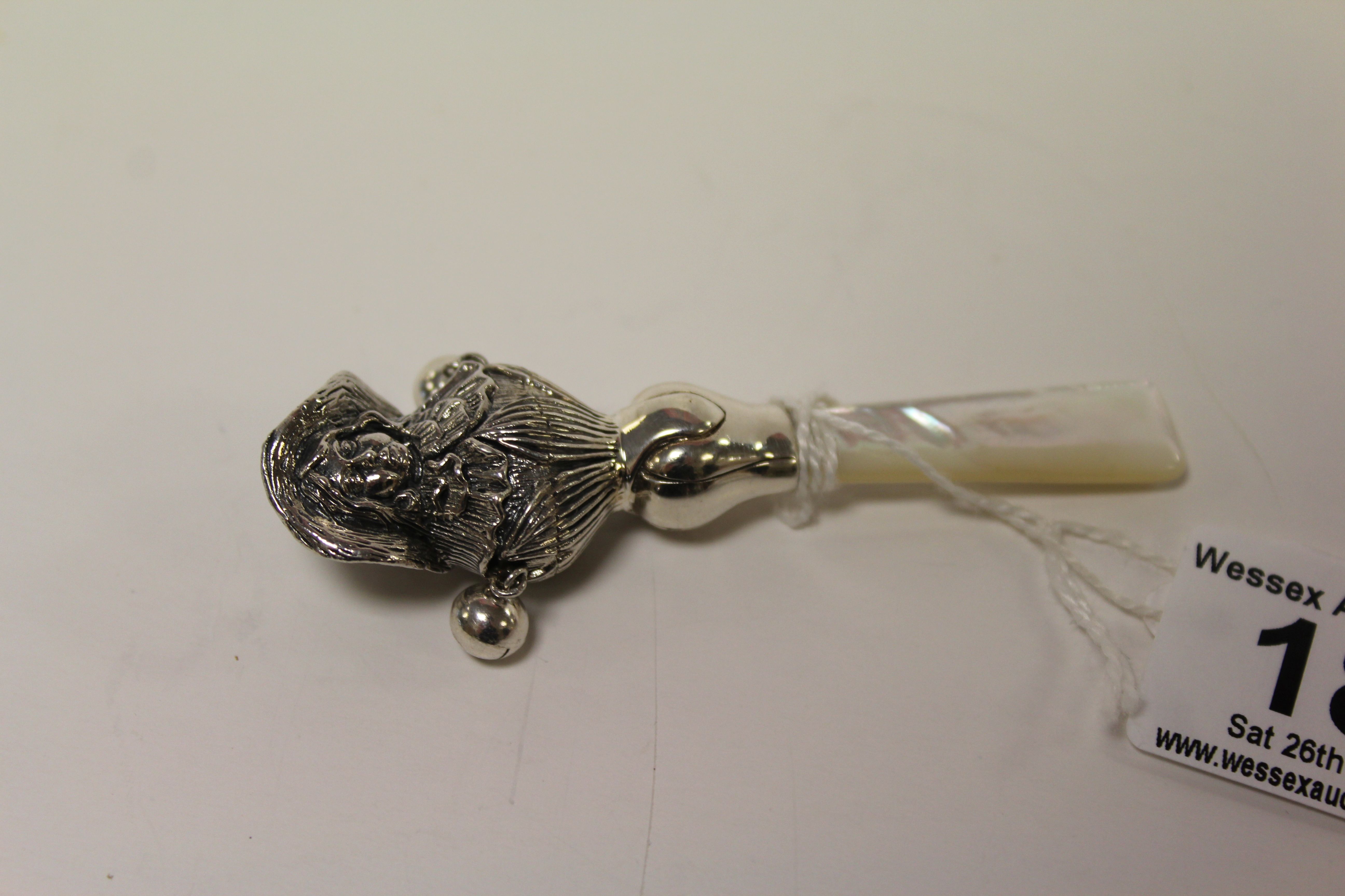 A silver babies rattle with mother of pearl handle.