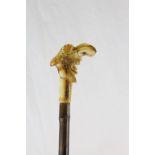 An antique walking stick with carved, grotesque bone head.