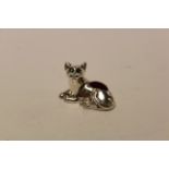 A silver cat pincushion with emerald eyes.