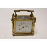 French brass carriage clock raised on four turned feet, white enamel dial with black Arabic