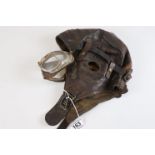 Vintage leather pilots helmet with associated goggles.