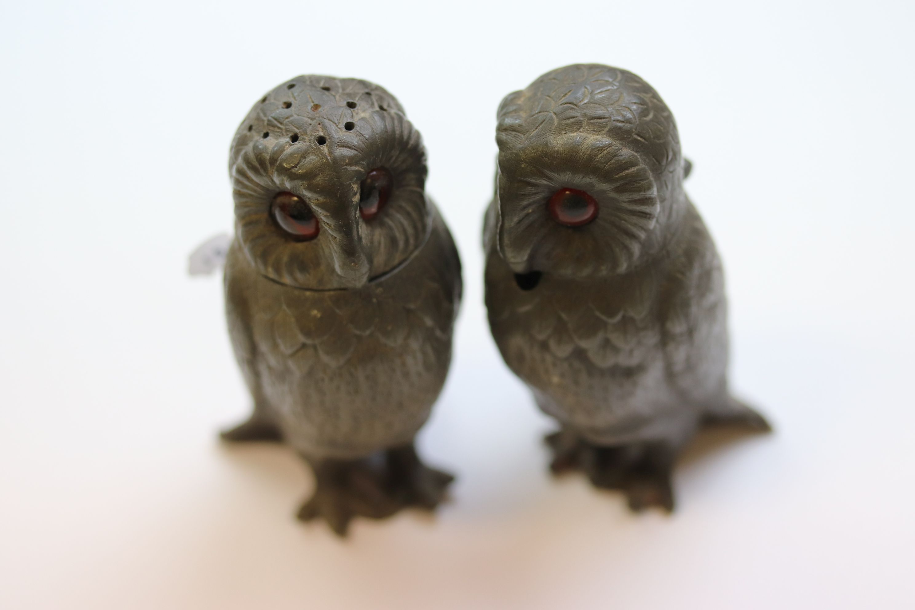 A part pewter owl cruet set comprising mustard and pepper, the owls with paste eyes and textured
