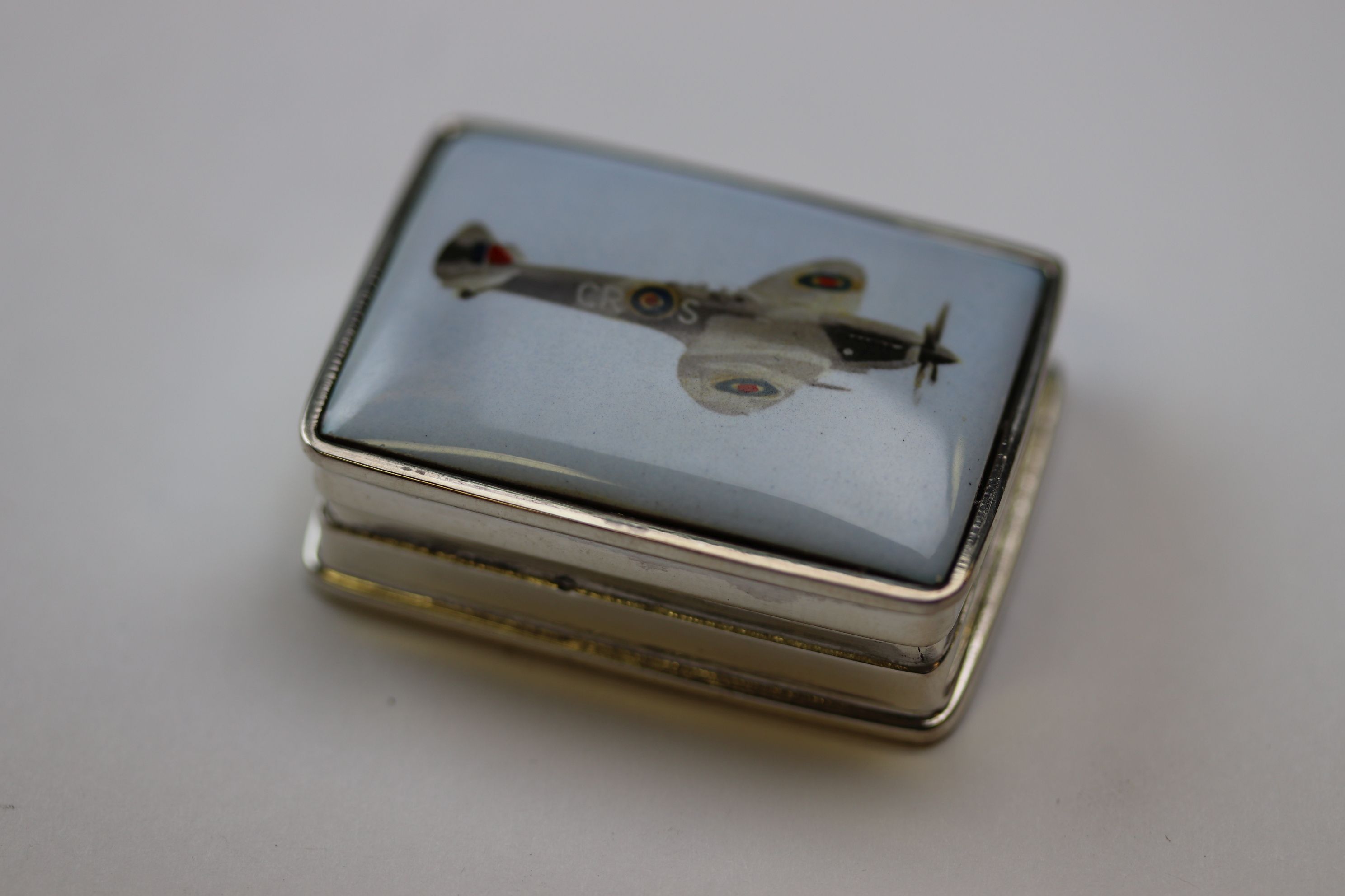 A silver pill box depicting Spitfire plane to the lid