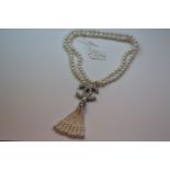 A long pearl necklace in the designer style with pearl and CZ tassels