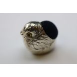 A silver pincushion in the form of a bird with glass eyes
