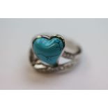 A silver ring set with a turquoise heart and CZs