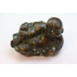 Oriental bronze figure of a reclining Budai, the body with small impressed circular faces,