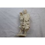 A Japanese Meiji period carved ivory okimono depicting a peasant holding a flowering trailing branch