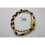 A graduated pearl, onyx and yellow bead necklace on silver clasp