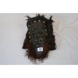 An early 20th century african tribal mask decoarted with wood , cowrie shells, vegetable fibres