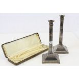 A pair of silver plated Corinthian column candlesticks on stepped square bases, foliate Acanthus