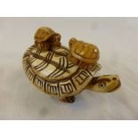 Bone carving of a turtle with two babies to shell