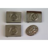 A Small Collection Of East German DDR Military Belt Buckles Along With A Badge With Maker Mark To
