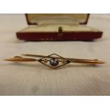 An Edwardian amethyst 9ct rose gold bar brooch, the central round mixed cut amethyst measuring