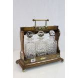 Oak cased three bottle Tantalus, with bottles and Silver plated mounts, fitted with carry handle and