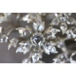 A diamond silver floral spray brooch comprising fifty-three rose cut diamonds, the principle diamond