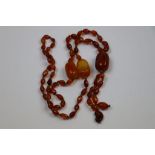 A long string of circa 1920s amber beads, comprising faceted clarified amber beads and three large