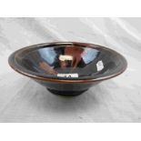 Studio pottery footed bowl of flared form with black and bronze oxidised glaze, stamped PG to