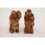 Pair of wooden netsukes, one depicting an Elder with child, the other depicting a man with fish,