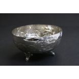 White metal bowl raised on three feet, repousse lion and stylised floral decoration, approximately