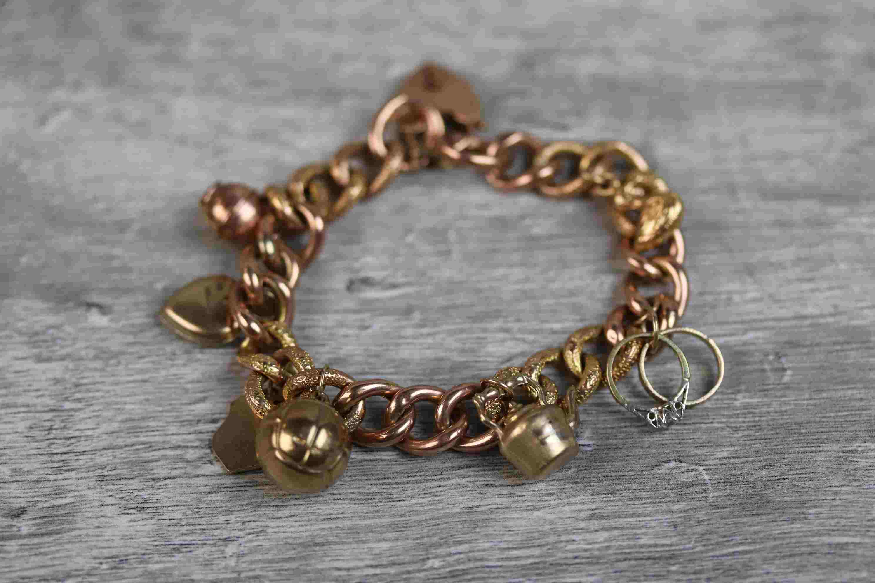 9ct rose gold curb link charm bracelet with 9ct rose gold padlock clasp, seven 9ct gold and yellow