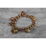 9ct rose gold curb link charm bracelet with 9ct rose gold padlock clasp, seven 9ct gold and yellow