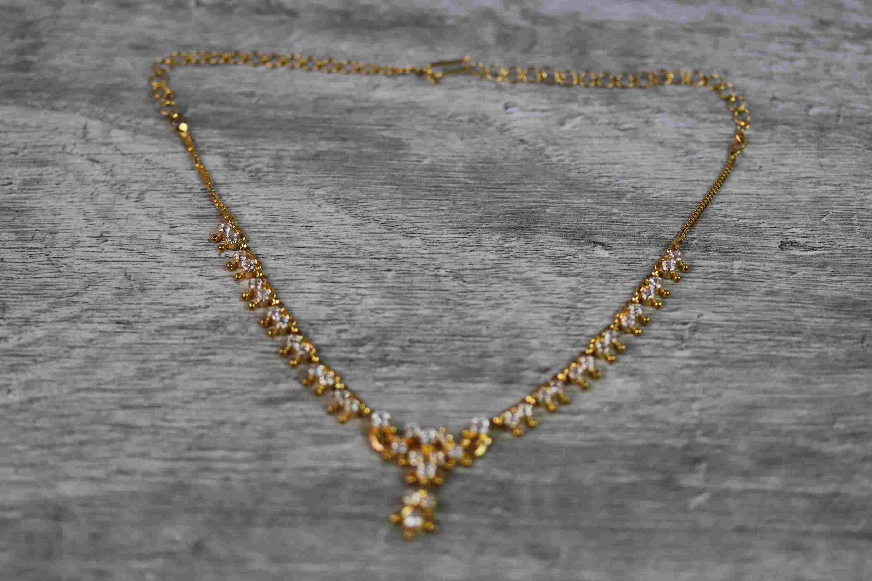 Indian yellow metal CZ fringe necklace, the central motif with suspended CZ cluster pendant drop,