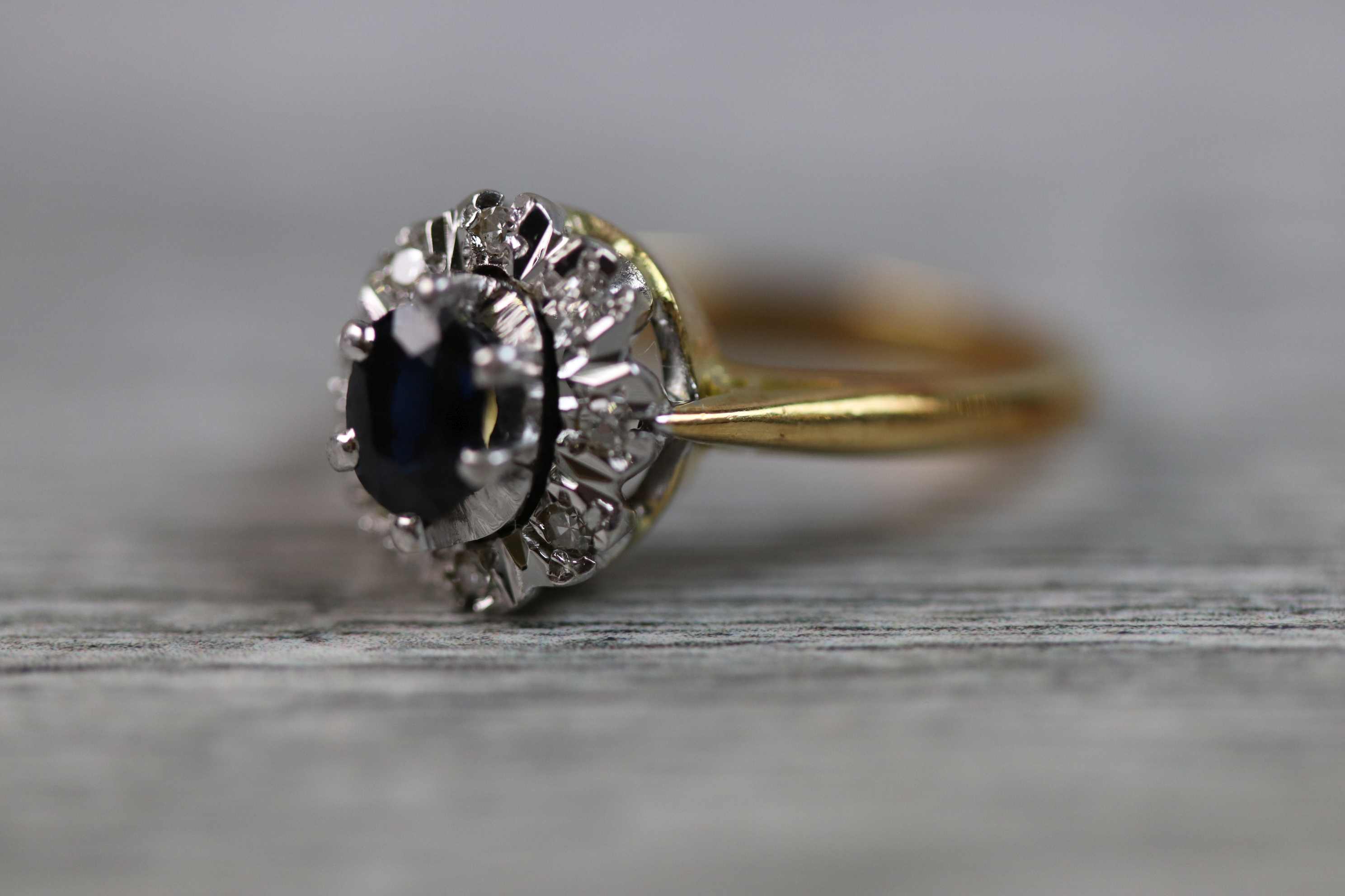 Sapphire and diamond 18ct yellow gold and white gold set cluster ring, the central blue-black oval