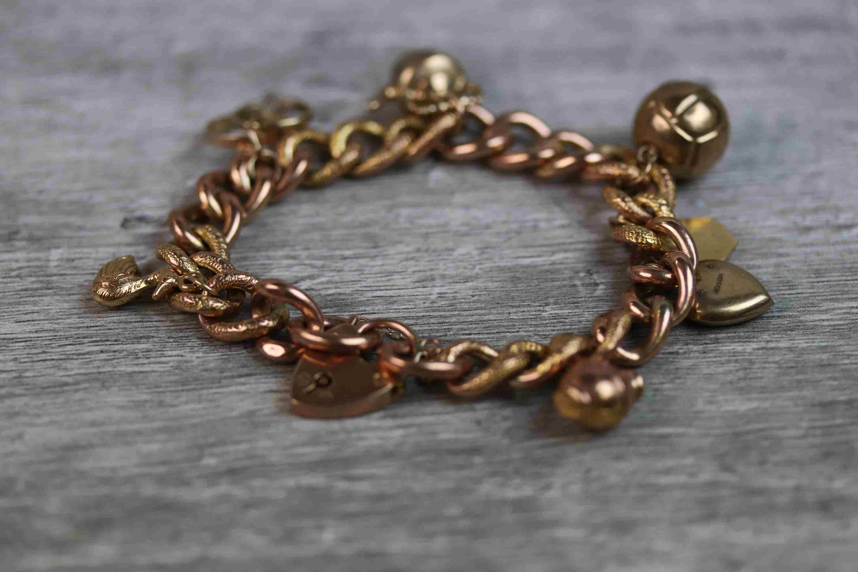 9ct rose gold curb link charm bracelet with 9ct rose gold padlock clasp, seven 9ct gold and yellow - Image 10 of 10