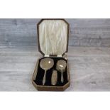 George V matched silver backed three piece dressing table brush set, comprising hand mirror, hand