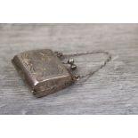 Silver novelty pill box in the form of a purse with finger chain, engraved foliate scroll